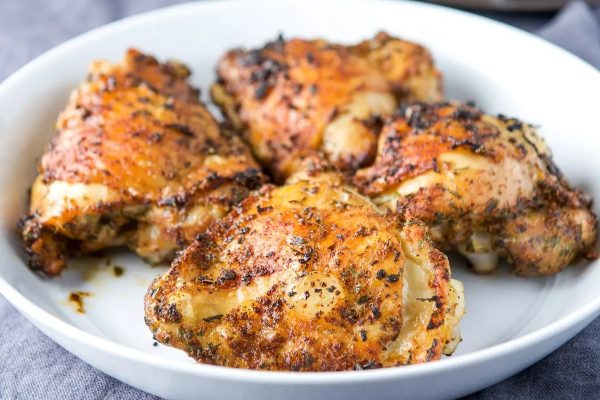 Chicken thighs in a white bowl on a table.