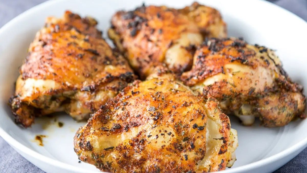 Chicken thighs in a white bowl on a table.