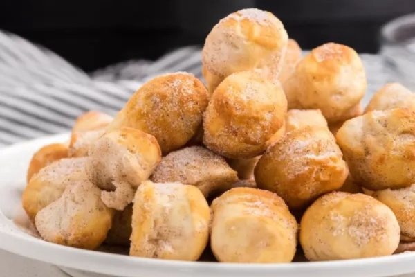 A plate of cinnamon sugar doughnuts with powdered sugar.