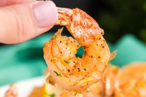 A person holding a shrimp on a plate.
