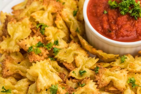 A plate of pasta with sauce and dipping sauce.