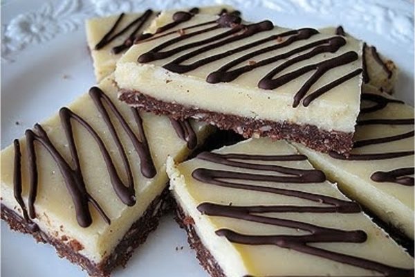 A plate of chocolate and cream cheese bars on a white plate.