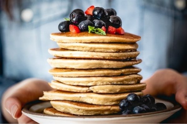 A stack of pancakes with berries on top.