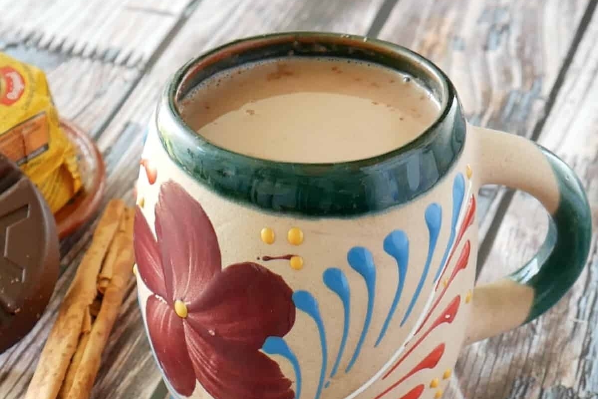 A mug of hot chocolate with cinnamon sticks and cocoa.