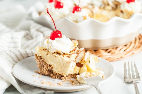A slice of pie with whipped cream and cherries on top.