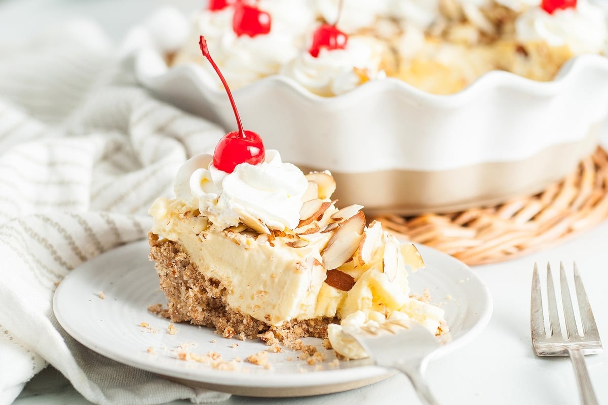 A slice of pie with whipped cream and cherries on top.