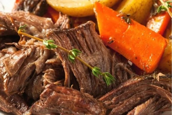 A plate of roast beef with carrots and potatoes.