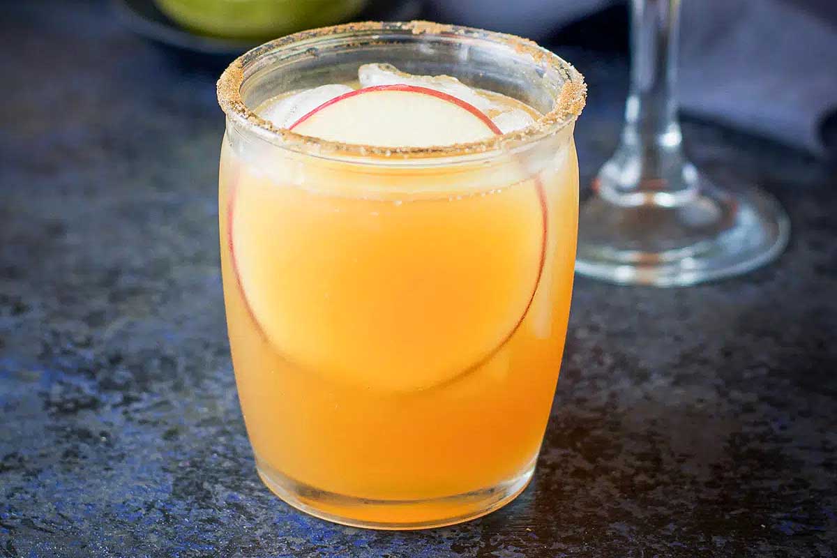 A refreshing glass of apple cider with a slice of apple, perfect for fall cocktails.