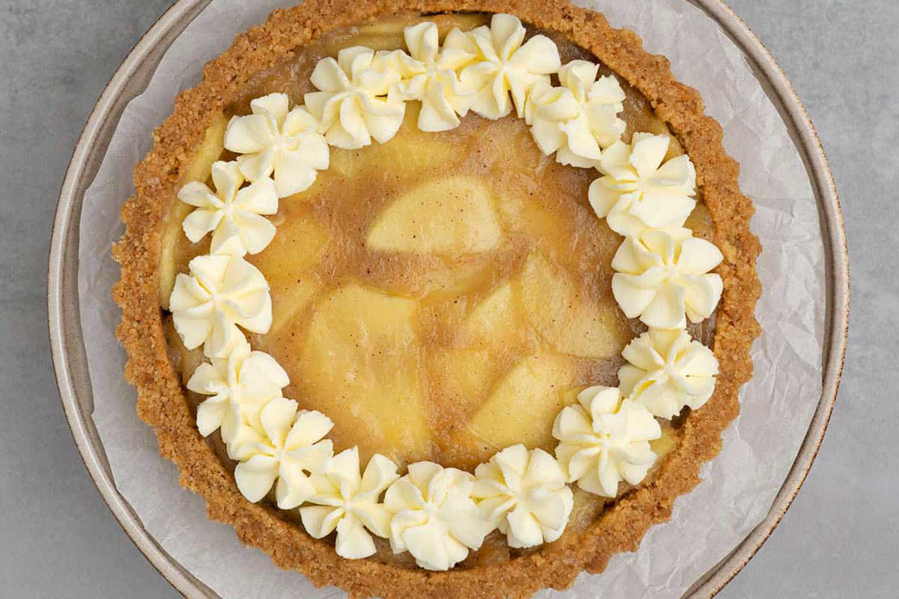 A tart topped with white icing and apples.
