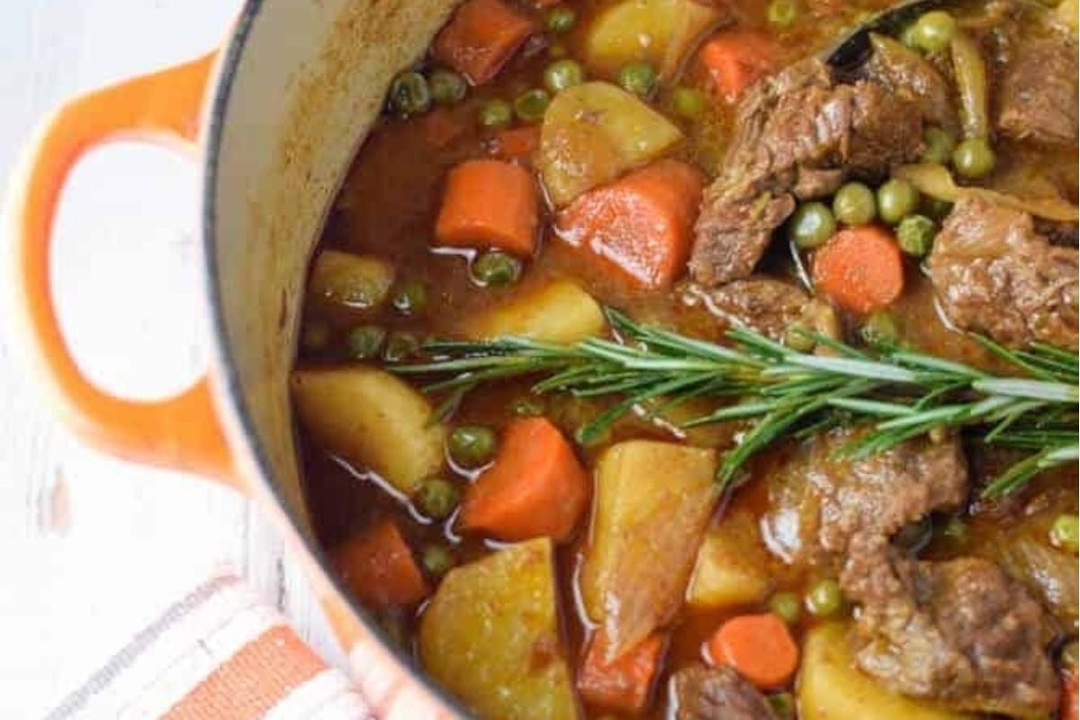 Mouthwatering beef stew cooked in an orange pot with hearty potatoes and vibrant carrots.