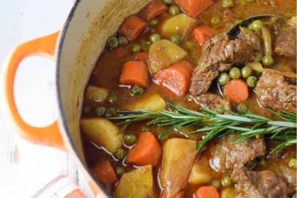 Beef stew in a pot with carrots and potatoes.