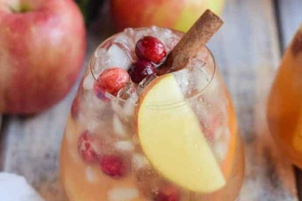 Two glasses of cranberry sangria with apples and cinnamon.