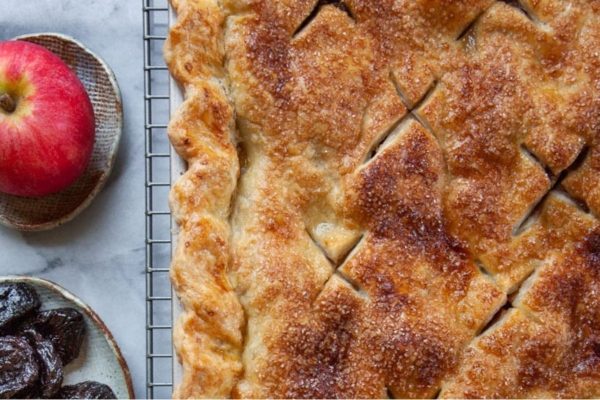 A pie with apples and raisins on a cooling rack.