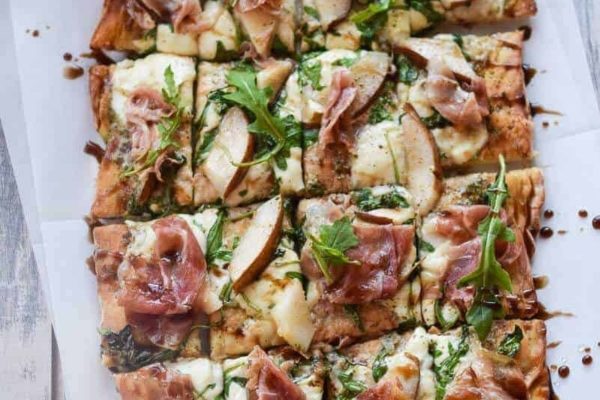 An Italian pizza with ham and cheese served on a white plate.