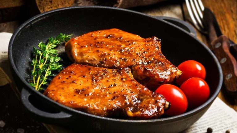 Asian-inspired pork chops in a skillet with tomatoes and herbs.