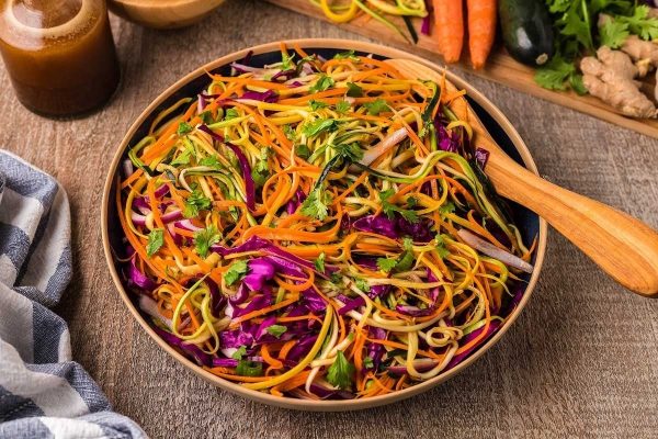 A colorful noodle salad on a wooden table.