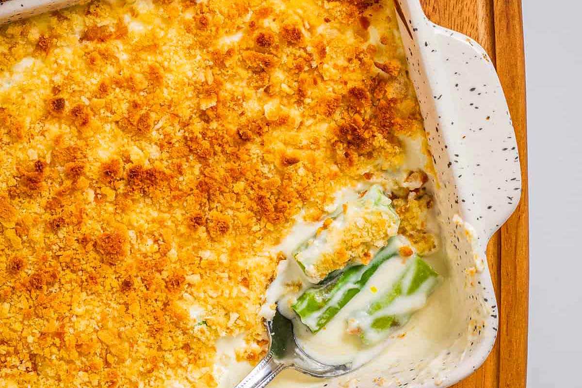 A casserole dish with a spoonful of cheesy green beans.