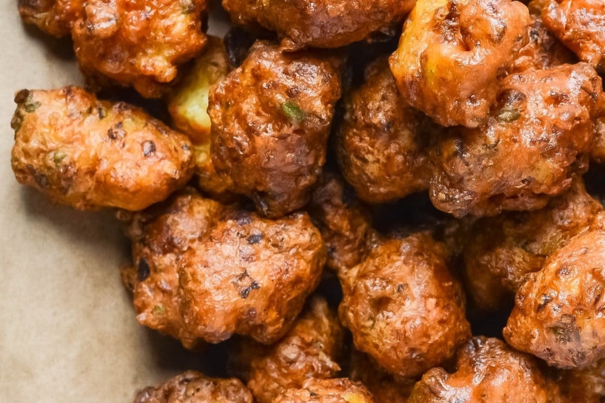 A mouthwatering pile of fried appetizers neatly arranged in a brown paper bag, perfect for Christmas parties.
