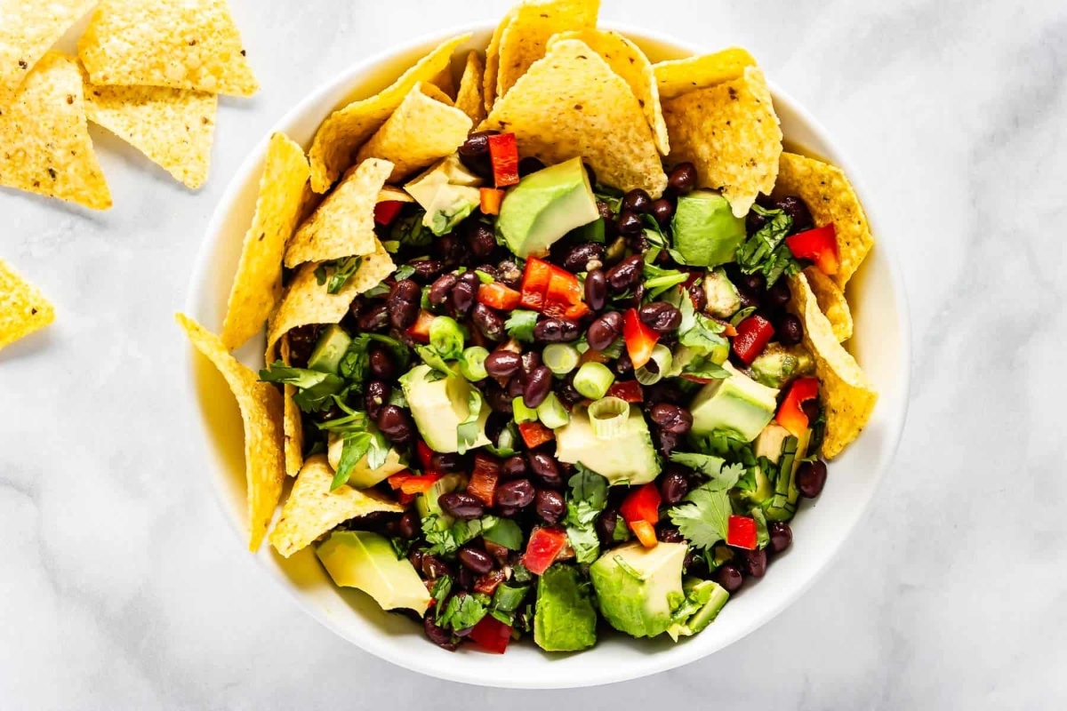 A bowl of black bean and avocado salad with tortilla chips.