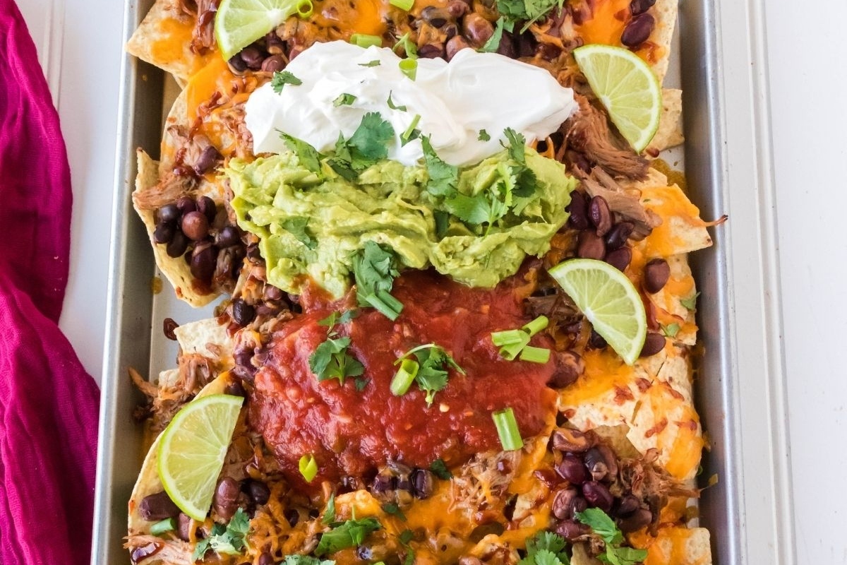 A tray of nachos with guacamole and sour cream makes for a delicious appetizer or snack.