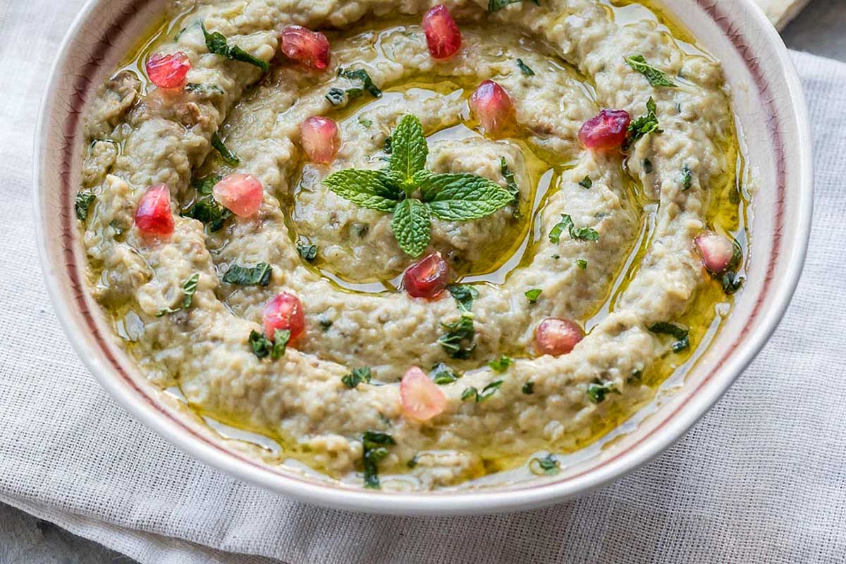 A bowl of hummus with pomegranate and pomegranate seeds.