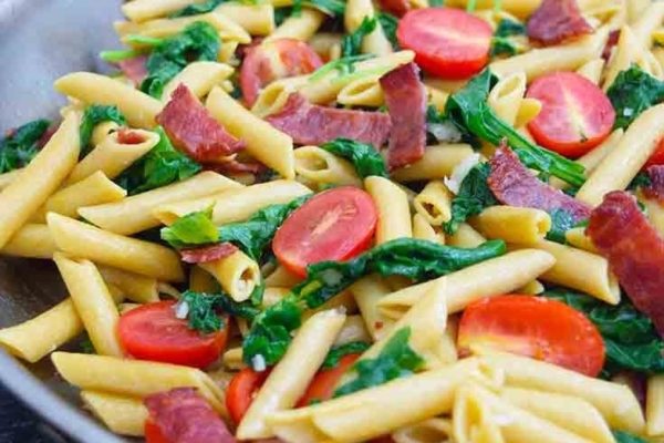 Penne pasta with bacon and tomatoes in a skillet, perfect recipe for a quick dinner.