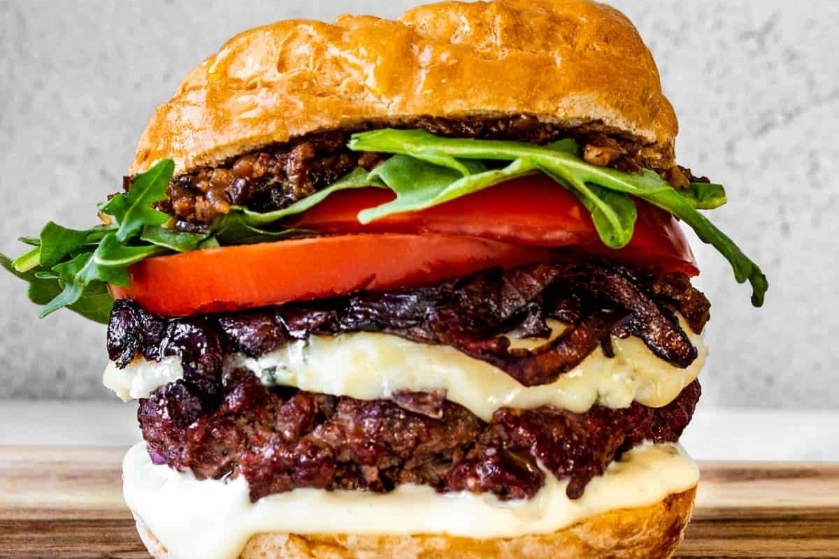 A burger served on a wooden cutting board.