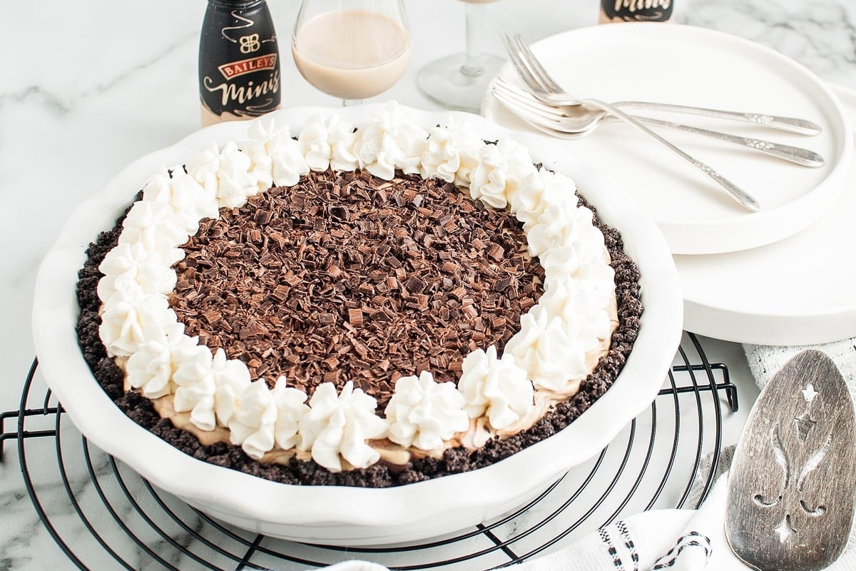 A white pie with whipped cream and chocolate on top.