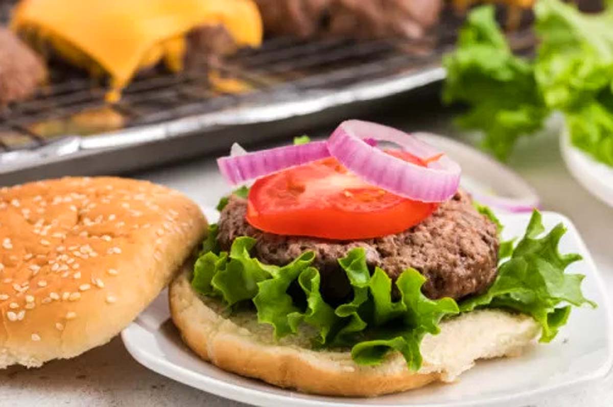 A hamburger on a plate next to a grill.