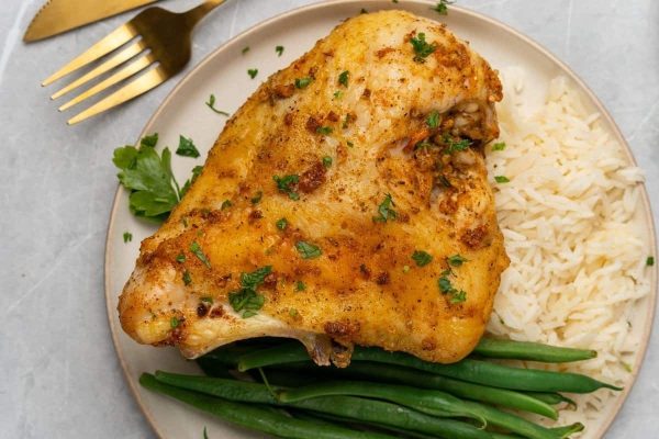 Boneless Chicken breast on a plate with rice and green beans.