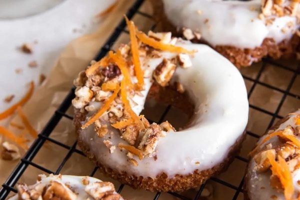 Donuts with icing and nuts on a cooling rack.
