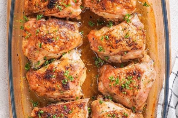 Chicken thighs in a baking dish with herbs.