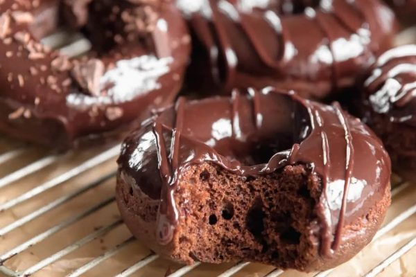 Chocolate glazed donuts on a cooling rack.