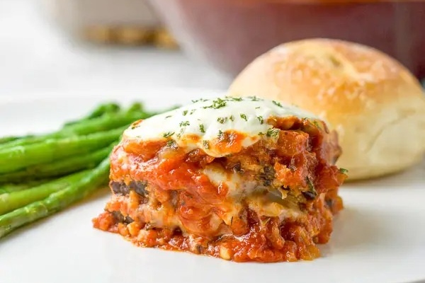 A plate with lasagna and asparagus on it.