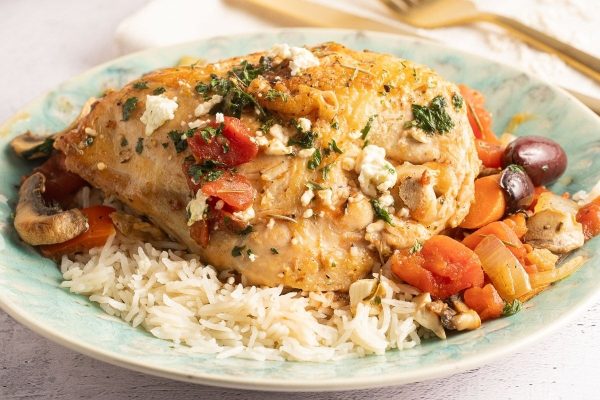 A bowl of rice with chicken and vegetables on it.
