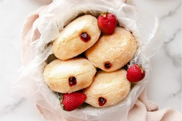 Strawberry doughnuts in a paper bag with strawberries.