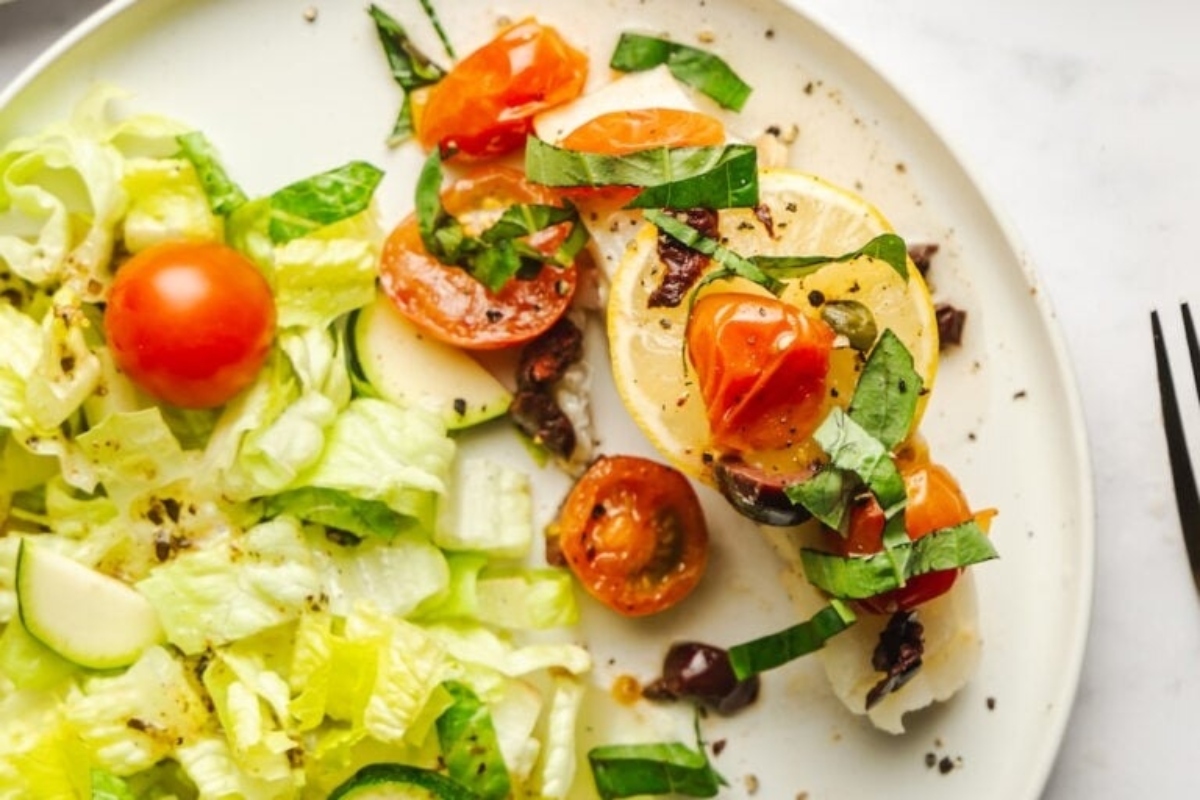 A feast of seven fishes, featuring a plate with fish, tomatoes, and salad.