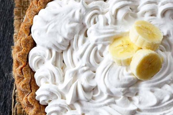 A banana pie with whipped cream and banana slices.