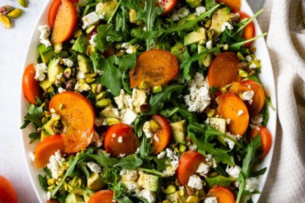 A colorful salad with carrots, feta and pistachios on a white plate.