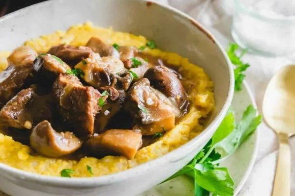 A bowl of mashed potatoes with mushrooms and gravy.