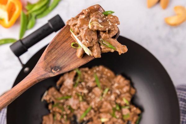 Chinese beef stir fry in a wok with oranges and cashews.