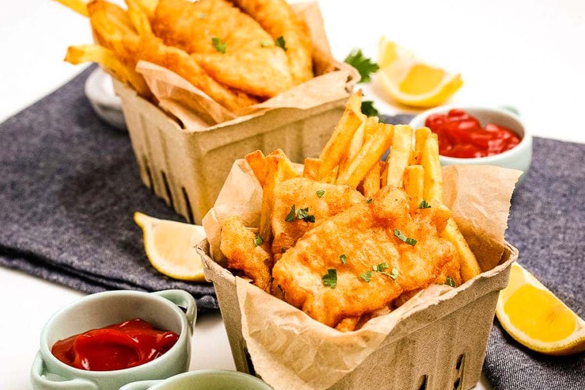 Pub-Style Fish and Chips served in a basket with lemon wedges and ketchup.