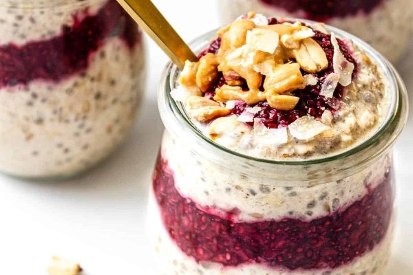 Two jars of breakfast meal prep with overnight oats, raspberries, and nuts.
