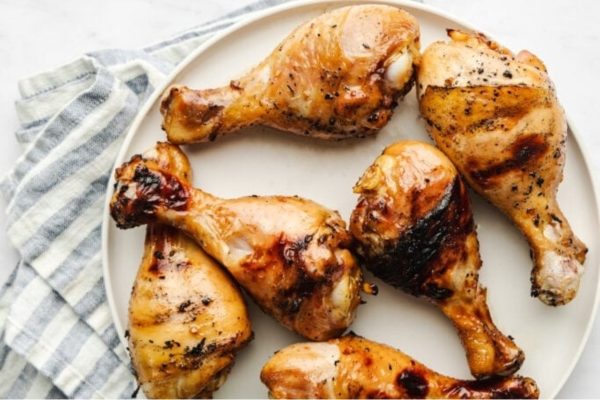 Grilled chicken legs on a plate with a napkin.