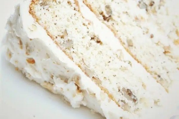 A slice of white cake topped with coconut shreds on a plate.