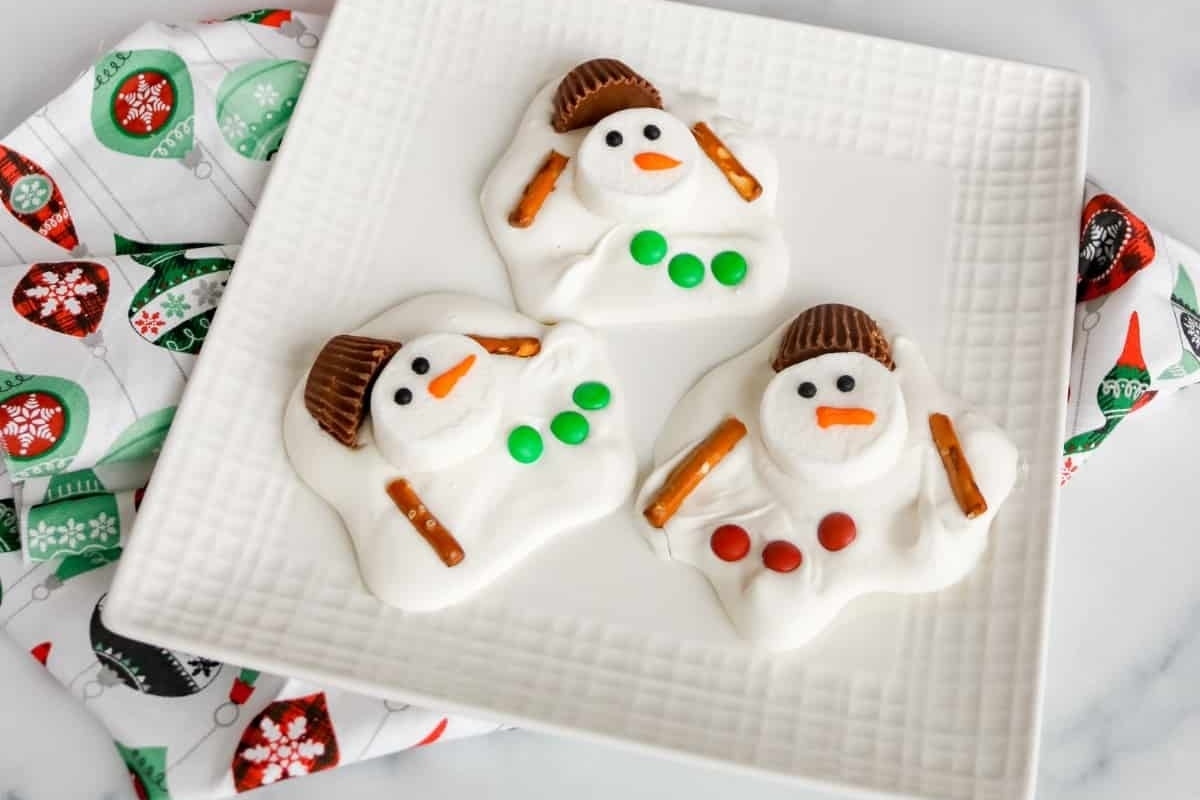 Three Christmas snowman cookies on a white plate.
