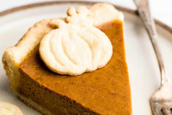 A slice of pumpkin pie on a plate with a fork.