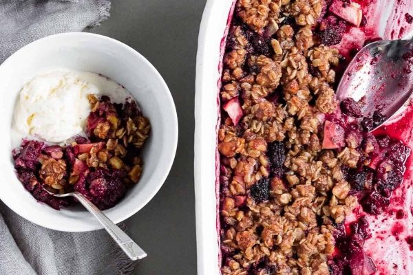 A dish of berry crumble with a scoop of ice cream.