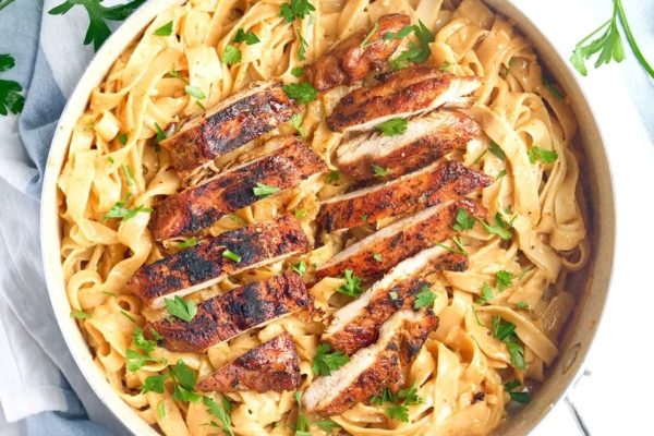 Chicken fettuccine in a skillet with parsley.