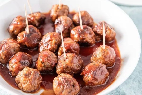 Meatballs in a white bowl with toothpicks.